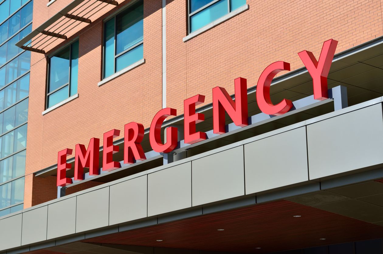 Hospital exterior with red EMERGENCY signage — the physical endpoint of every electronic claim that travels through 837 and 835 files